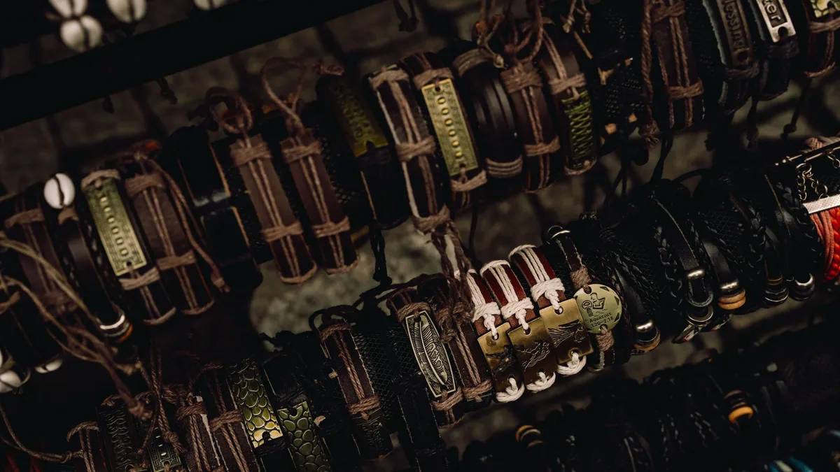 A collection of leather belts with metal buckles, hanging from a wall or rack in a store or market setting.